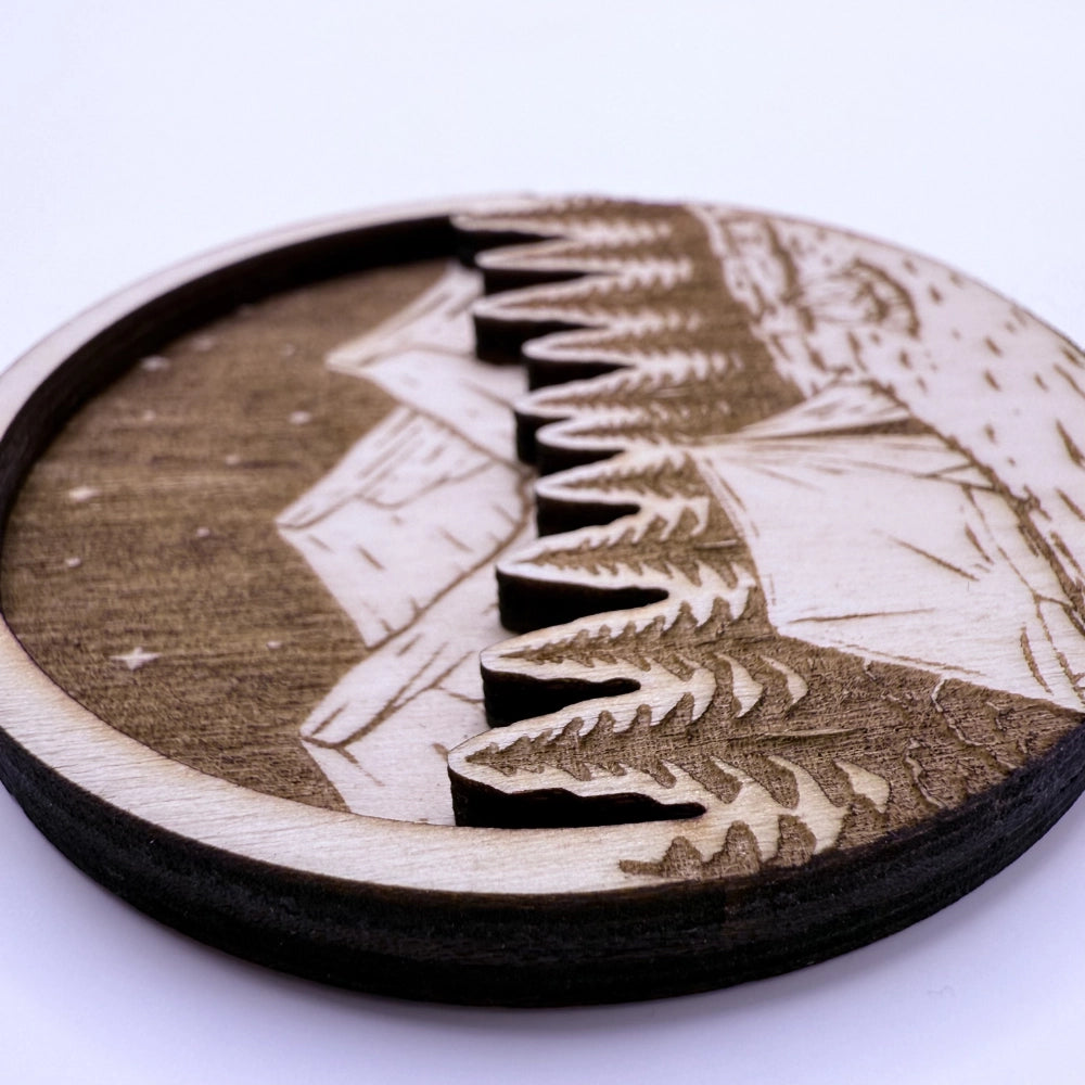 Runder, gravierter und per Laser-geschnittener Holzmagnet in zwei Schichten, mit Campingmotiv "Wald und Berge".
