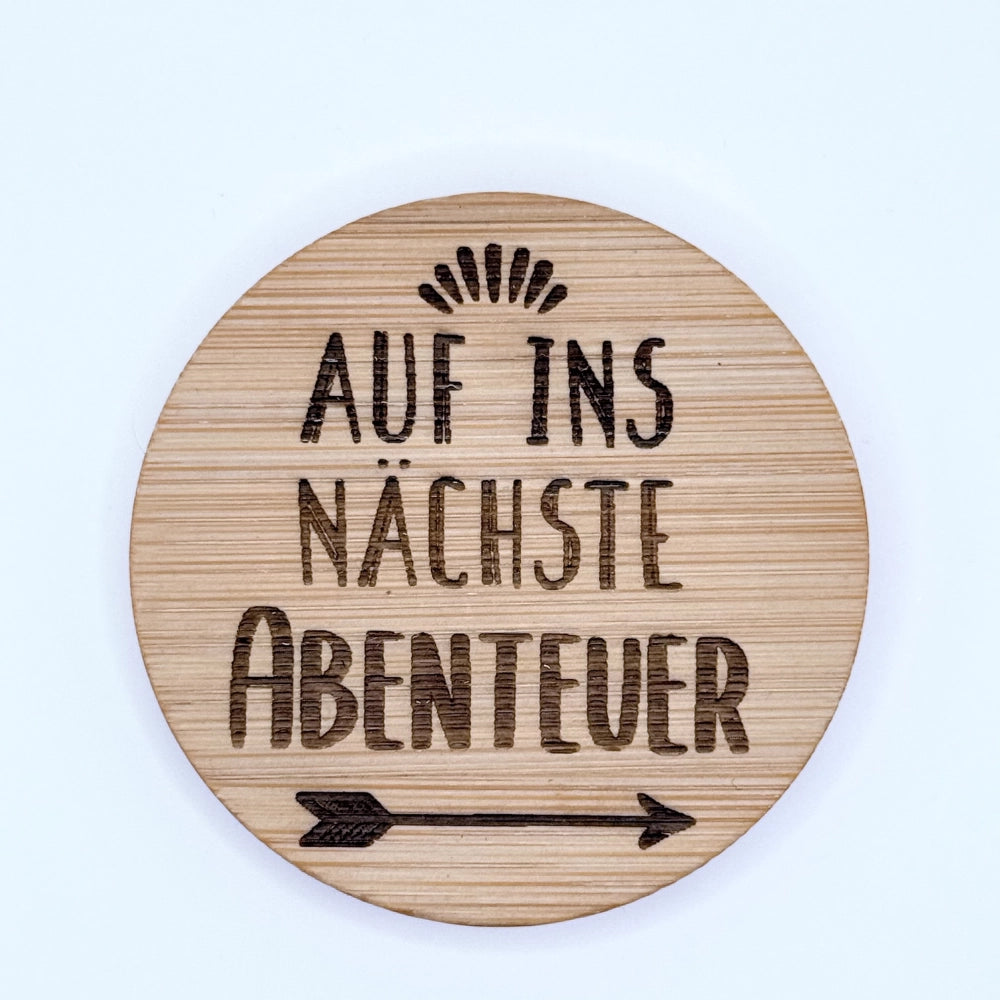 Runder Flaschenöffner-Magnet aus Bambus mit Gravur "Auf ins nächste Abenteuer".