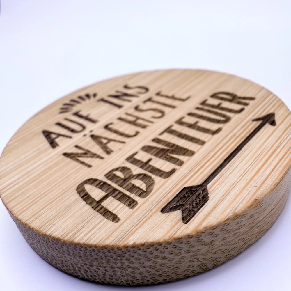 Runder Flaschenöffner-Magnet aus Bambus mit Gravur "Auf ins nächste Abenteuer".