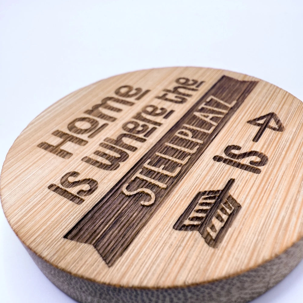 Runder Kühlschrank-Magnet aus Bambus  mit integriertem Flaschenöffner aus Metall auf der Rückseite. Vorne mit einer Gravur "Home is where the Stellplatz is"